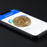 Coinbase Bitcoin Bottom with Bitcoin coin beside smartphone reflecting crypto trading volatility